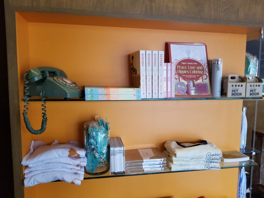 Shelves of a gift shop area featuring things like pet rocks, Jack Kerouac's 'On The Road', and hotel-branded t-shirts